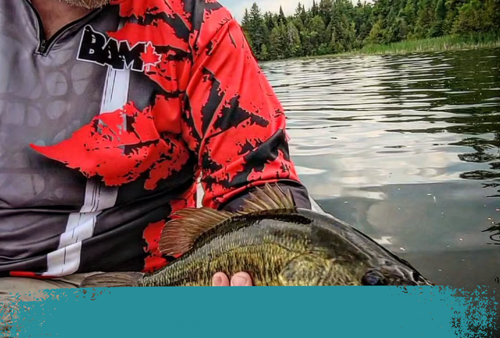 angler holding a fish and wearing Bambaits half zip up top